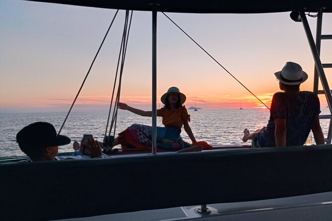 A catamaran under sail at sunset off the Cyclades